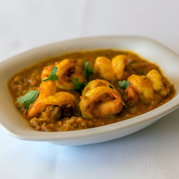 A white bowl filled with Nepalese shrimp curry, garnished with fresh cilantro.